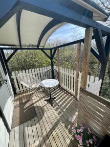 a wooden deck with a table and a chair on it at Pipowagen aan zee in Bergen aan Zee +2 photos
