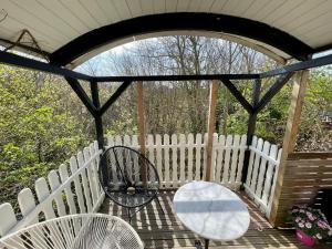 a porch with a white fence and a table and chairs at Pipowagen aan zee in Bergen aan Zee