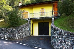 una casa gialla con una porta e un muro di pietra di Casa Vela a Ledro