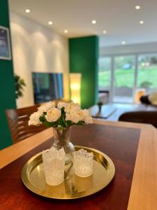 un jarrón con flores en una bandeja sobre una mesa en JUNIPRO Apartments Haustadt, en Beckingen
