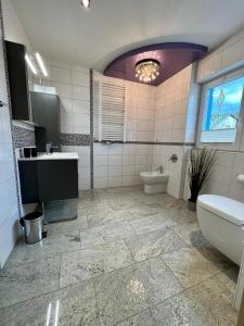 a bathroom with a sink and a tub and a toilet at JUNIPRO Apartments Haustadt in Beckingen