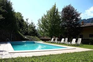 a swimming pool with lounge chairs next to a house at Casa Ornella in Ledro