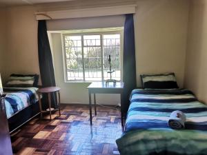 a room with two beds and a table and a window at Nandi's Place in Harrismith