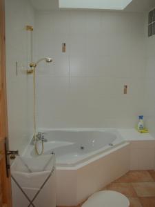 a white bathroom with a tub and a toilet at La Parrière in Le Saulcy