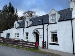 ein weißes Haus mit einem roten Briefkasten davor in der Unterkunft 1 Keepers Cottage Skeabost Bridge Isle Of Skye in Skeabost
