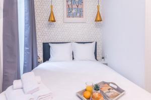 Una cama blanca con una bandeja de fruta. en Apartments WS Champs-Elysées - Colomb en París