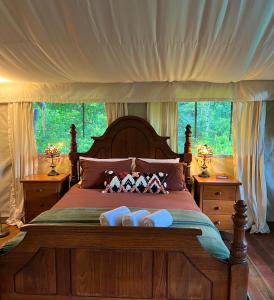ein Schlafzimmer mit einem großen Holzbett mit zwei Nachttischen in der Unterkunft Silk Pavilions Glamping in Mount Burrell
