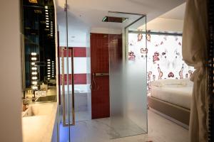 a bathroom with a glass shower and a bed at Ghibli Hotel in Civitanova Marche