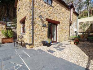 a stone house with a patio and a building at Blue Bell Cottage in St Austell