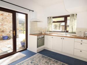 a kitchen with white cabinets and a large window at Blue Bell Cottage in St Austell
