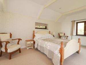 a bedroom with a bed and a chair and a window at Blue Bell Cottage in St Austell