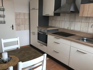 a kitchen with white cabinets and a sink and a stove at Helles Apartment in Quedlinburg