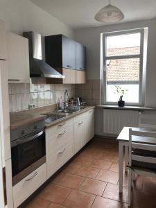 a kitchen with white cabinets and a sink and a window at Helles Apartment in Quedlinburg