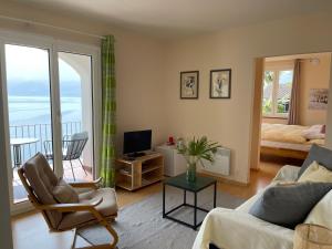 ein Wohnzimmer mit einem Sofa, einem TV und einem Balkon in der Unterkunft Residenza Bettina BnB & Ferienwohnungen in Ronco sopra Ascona