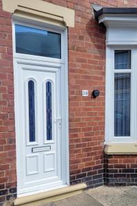 a white door on the side of a brick building at The Lawrence, 2 Bedroom Victorian House in Redcar