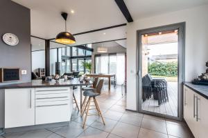 cocina abierta y comedor con mesa y sillas en Villa tout confort - Piscine - Montagnes - Lac - Parking, en Armoy