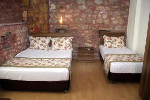 a bedroom with two beds and a stone wall at Odunluk Tas Konak Hotel in Dalyanköy