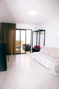 a white bedroom with a bed and a living room at Studio Jacaranda in Santiago del Teide