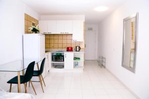 a kitchen with white cabinets and a table and chairs at Studio Jacaranda in Santiago del Teide