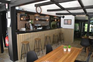 un bar con mesas de madera y taburetes en un restaurante en Camping Les Roussilles, en Saint-Sylvestre