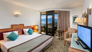 a hotel room with a bed and a flat screen tv at Özkaymak Falez Hotel in Antalya