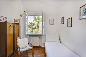 a bedroom with a bed and a chair and a window at Villa Rica by Wonderful Italy in Santa Margherita Ligure