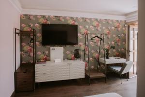 Ein Wohnzimmer mit einem Fernseher an der Wand, umgeben von Blumen. in der Unterkunft Matiana Estudiante in Zacatecas