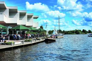 mensen in een restaurant naast een lichaam water bij Hotel Princenhof in Earnewâld