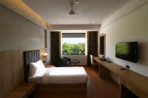 um quarto de hotel com uma cama e uma televisão em HOTEL KLG ALTORIA em Chandīgarh