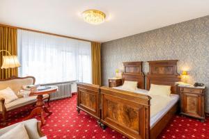 a bedroom with two beds and a couch and a table at Kurhotel & Hotel Mozart in Bad Gastein
