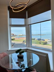 a glass table with a potted plant in front of a window at Eden Retreats Serviced Apartments in Morecambe