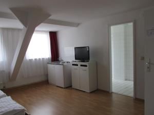 una sala de estar con TV y una habitación con ventana en Hotel Westend, en Colonia