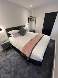 1 dormitorio con 1 cama grande con sábanas y almohadas blancas en Eden Retreats Serviced Apartments en Morecambe