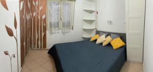 una camera da letto con letto blu e cuscini gialli di Casa vacanze Anticaglie a Punta Secca