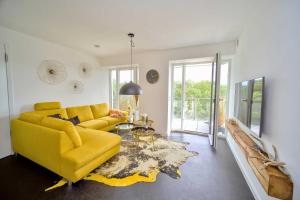 een woonkamer met een gele bank en een tafel bij FeWo Prora - Hiddensee 4.2 in Binz