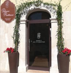 een deur naar een restaurant met twee grote bloempotten bij Palazzo Rattazzi in Monopoli