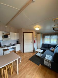a living room with a blue couch and a kitchen at Mälarhusen Semesterby Österlen - Stugor & Gårdssviter in Sandby +44 photos