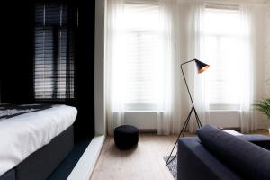 a bedroom with a bed and a lamp and a couch at Maison Nationale City Flats & Suites in Antwerp