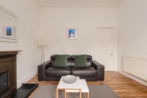 a living room with a leather couch and a coffee table at The London Road Apartment - 2BR/1BA in Edinburgh +7 photos