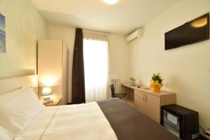 Schlafzimmer mit einem Bett, einem Schreibtisch und einem TV in der Unterkunft Hotel Ristorante La Marina Mhotelsgroup in San Bartolomeo al Mare