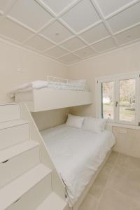 a white bedroom with two bunk beds in it at KAVET Palio Cottage in Paleo Tsifliki