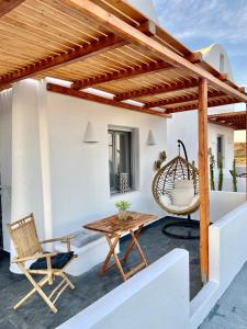 un patio con pérgola de madera, mesa y silla en Aeron Suites, en Éxo Goniá