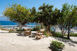 un patio con mesas, sillas, árboles y el océano en Luxury Apartment Marine View, en Agios Nikolaos