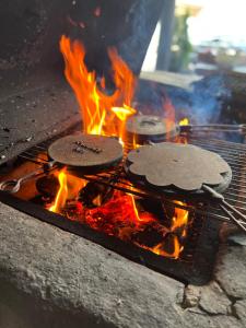 two hamburgers are cooking on a grill with fire at J A Ranch Bed & Breakfast in Strömsnäsbruk