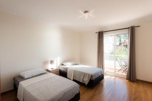 two beds sitting in a room with a window at Sunnyside Villa in Arco da Calheta +17 photos
