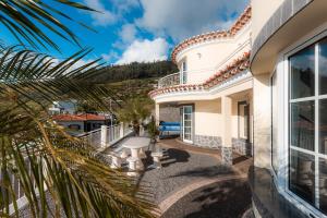 Blick auf ein Haus mit einer Palme in der Unterkunft Sunnyside Villa in Arco da Calheta