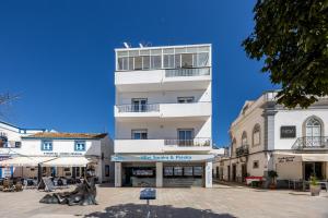 a tall white building with a statue in front of it at Casa do Mercado in Olhão
