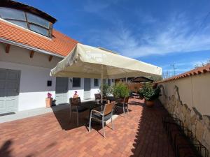 a patio with a table with chairs and an umbrella at Szkíta Panzió in Balatonmáriafürdő