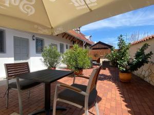 a patio with a table and chairs and an umbrella at Szkíta Panzió in Balatonmáriafürdő