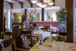 a restaurant with tables and chairs and a pink couch at Hotel Landhaus Pollmeyer in Friesoythe